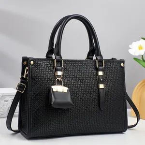 Close-up of black textured leather handbag featuring golden hardware and a mini charm