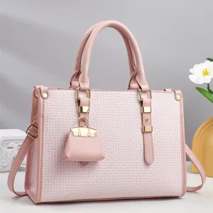 Detail of pink textured leather tote bag featuring elegant gold hardware and small charm