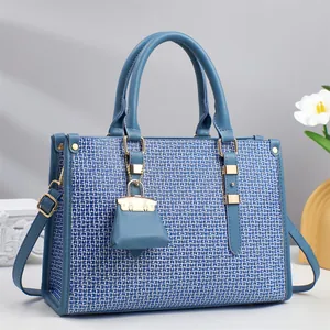 Close-up of blue geometric patterned tote bag with leather handles and gold hardware details