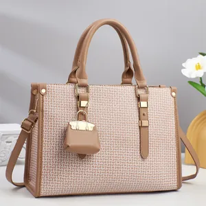 Detail of elegant two-tone textured leather tote bag with gold hardware and mini charm