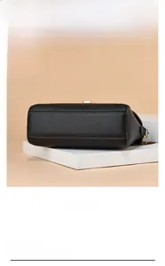 Détail du fond du sac en cuir noir motif litchi et boucle métallique dorée