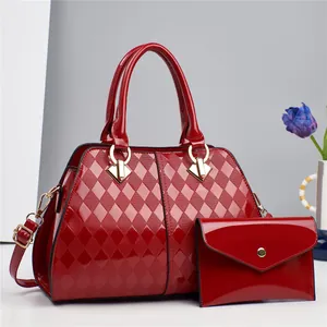 Detalle del conjunto de bolso rojo de charol acolchado con sobre de mano a juego y herrajes