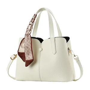 Elegant white faux leather tote bag with silk scarf and adjustable strap on white background