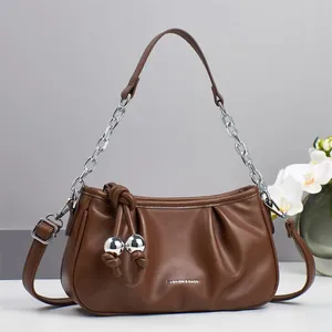 Détail du sac nuage en cuir marron foncé avec chaîne argentée et nœud décoratif