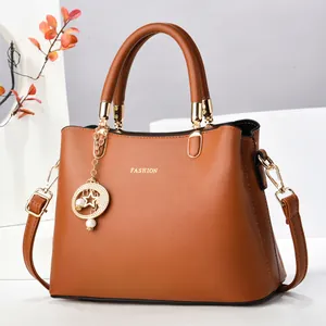 Détail du sac à main en cuir PU caramel avec lettrage doré et breloque élégante