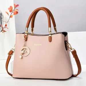 Sac à main rose en cuir grainé avec poignées marron et logo doré élégant en relief
