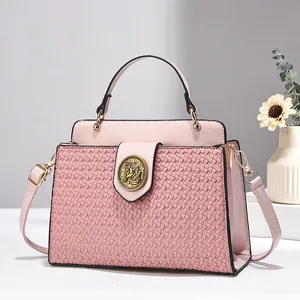 Détail du sac rose en similicuir avec texture tressée et emblème licorne dorée