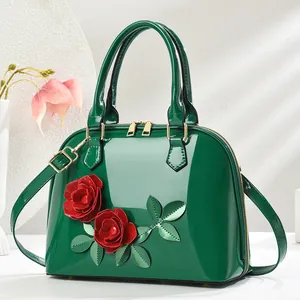 Détail du sac à main vert foncé avec roses 3D rouges et garnitures dorées