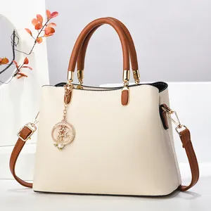Détail du sac cabas beige avec anses marron et accessoire de breloque étoile et lune dorée