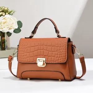 Détail du sac marron avec texture crocodile, fermoir doré rotatif et picots de protection