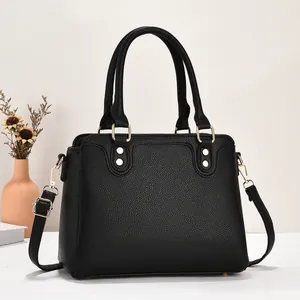 Klassische schwarze Lederhandtasche mit goldenen Beschlägen und Schultergurt in Studio-Ambiente