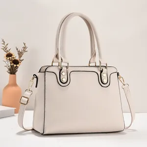 Detail der beigen Handtasche aus Kunstleder mit Lychee-Narbung und goldenen Beschlägen
