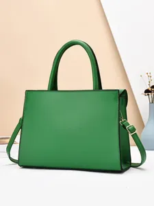 Detail van levendige groene trapezium handtas met gouden hardware en afneembare riem