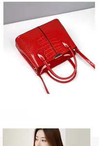 Detail of red crocodile pattern handbag with dual handles and polished metallic buckle