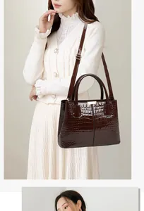 Close-up of deep brown crocodile pattern faux leather handbag with golden metal hardware
