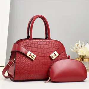 Detail of red embossed crocodile texture handbag with gold hardware and small pouch
