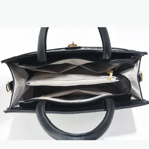 Détail intérieur du sac à main noir montrant plusieurs compartiments et doublure à vagues