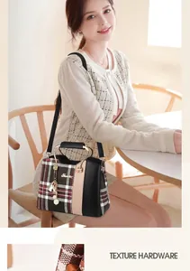 Detail view of plaid patchwork handbag showing metal handles and side tassel ornament