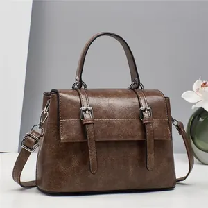 Detail of vintage dark brown tote bag with distressed PU leather texture and buckles