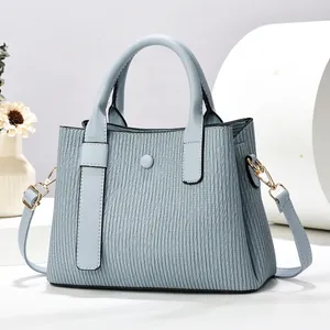 Borsa a mano azzurra con trama a pieghe e tracolla regolabile in un set fotografico