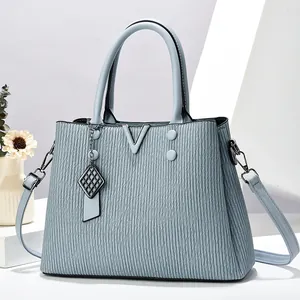 Sac à main bleu clair avec texture verticale et pendentif métallique en forme de V