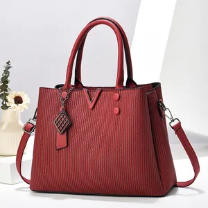 Détail du sac à main en cuir texturé rouge avec une boucle métallique élégante en forme de V