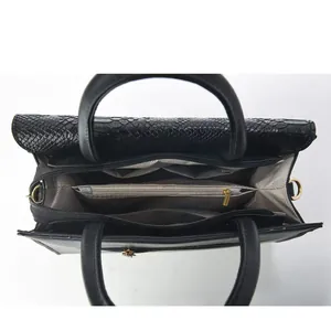 Vista interior del bolso tote negro con compartimentos organizados y textura serpiente