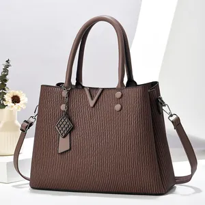 Vue détaillée du sac à main marron chocolat tissé avec fermoir en V et pendentif en maille