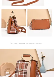 Detail of plaid tote bag showing metal arch handles and bottom anti-wear studs