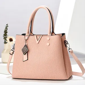 Détail d'un sac cabas en PU rose avec textures verticales et un charm métallique en V