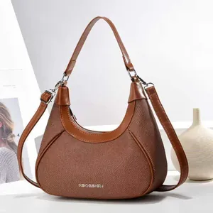 Detailed view of brown crescent shoulder bag with mixed twill and leather texture