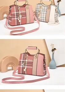 Detail of pink plaid handbag showing metallic ring handles and tassel pendant decoration