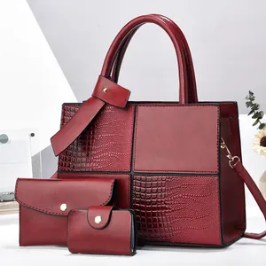 Detail of burgundy three-piece bag set featuring smooth and crocodile embossed textures