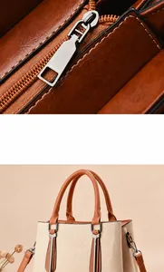 Detail van zilveren rits en bruine leren bies op crèmekleurige canvas handtas met stiksels