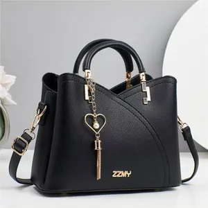 Elegant black pebbled leather tote bag with golden hardware and heart pearl charm