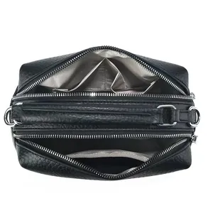 Detail view of large black lychee leather handbag with three zipper compartments and silver hardware
