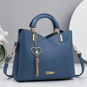 Detail of dark blue tote bag showing lychee grain texture and heart tassel charm
