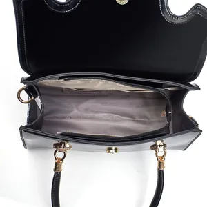 Détail du sac à main en cuir verni brillant avec fermoir doré et doublure grise