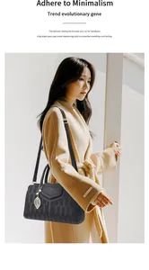 Détail du sac Boston en cuir gaufré noir avec pendentif feuille dorée et logo de marque