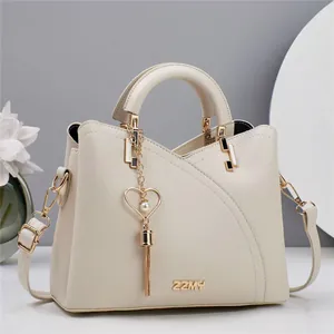 Detail of cream leather handbag with pearl heart charm and gold-toned metal ZZMY logo