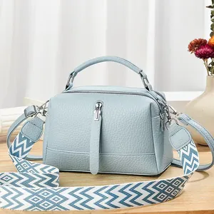Detail of light blue lychee pattern handbag with stylish wide woven geometric shoulder strap