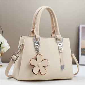 Détail du sac à main en texture tissée avec fermoir argenté et breloque fleur en cuir