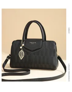 Détail du sac en cuir gaufré noir avec pendentif feuille dorée et logo poli