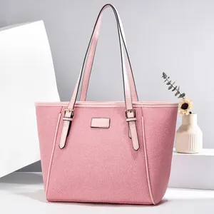 Detailed close-up of pink woven tote bag with leather handles and gold metal hardware