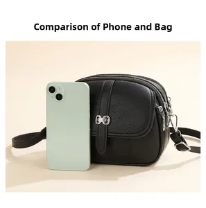 Size comparison of black leather crossbody bag with silver buckle and smartphone