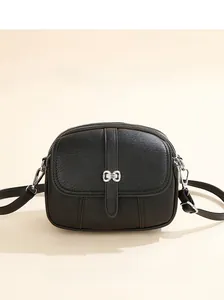 Detail of a black PU leather round bag featuring a silver bow buckle and textured finish
