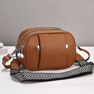 Détail d'un sac bandoulière en cuir grainé marron avec trois couches et sangle large
