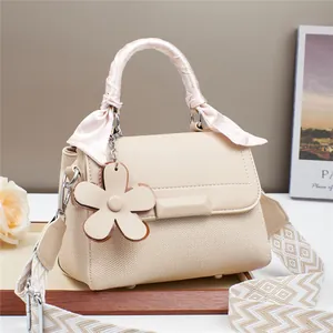 Sac à main élégant en toile et cuir crème avec pendentif floral et décoration foulard