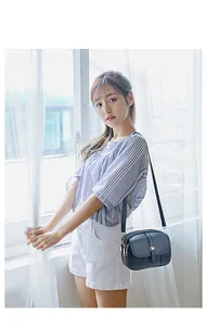 Detailed view of dark blue multi-zipper leather crossbody bag with metal bow detail