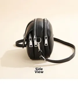 Side view of black faux leather crossbody bag with three zipper compartments and silver hardware